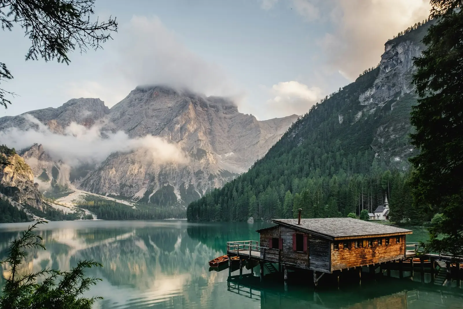 A wooden cabin beside a still mountain lake