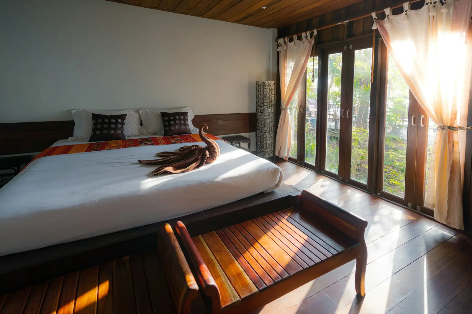 A hotel bed dressed in white linen under warm light